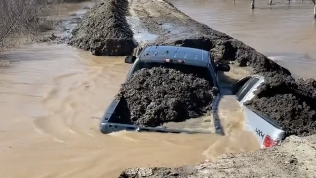 Screenshot of two pickup trucks filled with dirt used to plug up a broken levee
