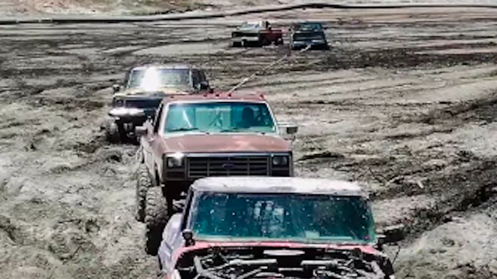 five off-roading trucks roped together to rescue friends stuck in the mud